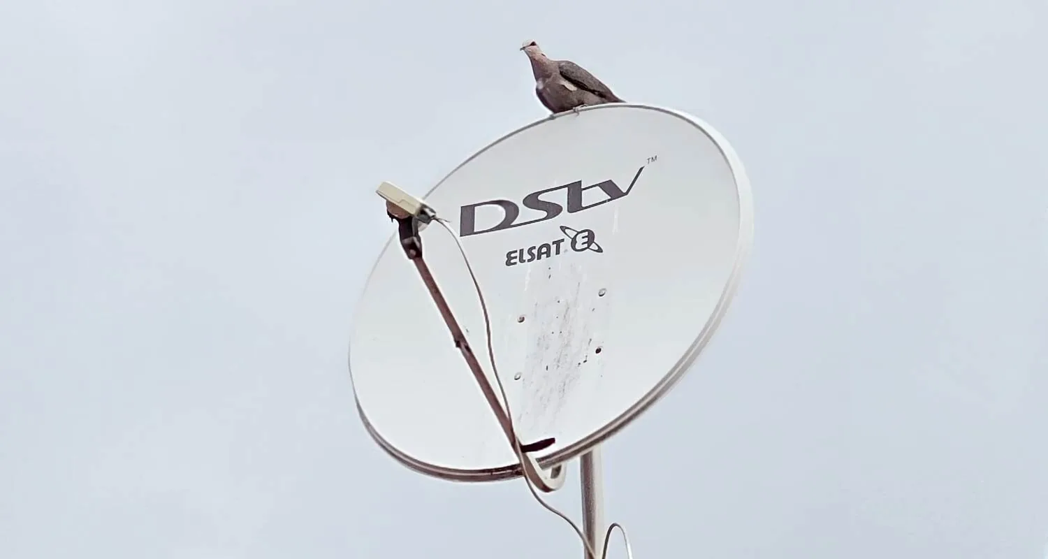 Technician installing a DSTV satellite dish on a home